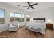 This bright main bedroom offers a ceiling fan, wood-look floors, a window view and bench seating at the foot of the bed at 10607 E Hillside Mine Ct, Gold Canyon, AZ 85118