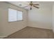 Bright bedroom featuring neutral carpeting, a ceiling fan, and a window offering views of the outdoors at 1937 W Burgess Ln, Phoenix, AZ 85041