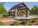 Covered picnic area with stone pillars, picnic tables, trash can, green grass, and green shrubs at 2588 E Grenache Rd, San Tan Valley, AZ 85143