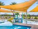Vibrant splash pad at community pool, boasting a slide and sunshade, promises fun for all, with lounge chairs around the perimeter at 2644 E Grenache Rd, San Tan Valley, AZ 85143