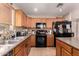 Functional kitchen featuring wood cabinets, black appliances, and tiled floors at 298 W Dana Dr, San Tan Valley, AZ 85143