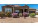 Beautiful home with a well-manicured desert landscape featuring flowering bushes and a covered entryway at 38005 W Montserrat St, Maricopa, AZ 85138