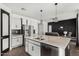 Open-concept kitchen with black and white cabinets, stainless steel appliances, and eat-in island at 38005 W Montserrat St, Maricopa, AZ 85138