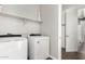 Bright laundry room featuring side-by-side white washer and dryer and shelves at 38005 W Montserrat St, Maricopa, AZ 85138