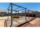 Backyard space with a metal pergola, wooden planters, and low-maintenance desert rock landscaping at 38005 W Montserrat St, Maricopa, AZ 85138