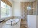 Large soaking tub with picture window in primary bathroom featuring earth-tone tile work at 3812 E Camelback Rd, Phoenix, AZ 85018