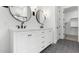 Bright bathroom featuring dual vanity with black fixtures, round mirrors, and access to a walk-in closet at 4451 N 203Rd Ave, Buckeye, AZ 85396