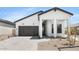 Charming white home featuring a gray garage door, covered porch, and desert landscaping at 4451 N 203Rd Ave, Buckeye, AZ 85396