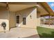 A covered patio area featuring a white door, small window, landscaping, and a beige stucco wall at 4790 E Navajo St, Phoenix, AZ 85044