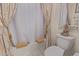 This cozy bathroom features a shower/tub with decorative, light-colored curtain and Buddha statue on the toilet at 5218 N Tiller Dr, Litchfield Park, AZ 85340