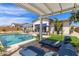Relaxing poolside view with lounge chairs, patio cover, and artificial turf landscaping at 5218 N Tiller Dr, Litchfield Park, AZ 85340