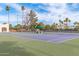 View of blue and green tennis courts with palm trees and a covered bench at 5218 N Tiller Dr, Litchfield Park, AZ 85340