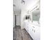 Bright bathroom featuring double sinks, white cabinetry, wood-look flooring, and framed mirrors and shower with glass door at 537 S 153Rd Ln, Goodyear, AZ 85338