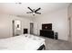 Carpeted bedroom with TV set, ceiling fan, ensuite bath, and natural light from white-painted walls at 537 S 153Rd Ln, Goodyear, AZ 85338