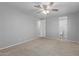 A bright, carpeted bedroom with an overhead fan, neutral colors, and an en-suite bathroom for added privacy at 5436 E Aspen E Ave, Mesa, AZ 85206