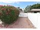 Backyard with a white gate, lush green bushes with pink flowers, and gravel at 5720 E University Dr, Mesa, AZ 85205