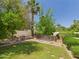 Grassy backyard with mature trees, brick-lined firepit, and lush landscaping at 5905 E Donna Ln, Paradise Valley, AZ 85253