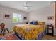 Bright bedroom featuring a ceiling fan, window with shutters, and a queen bed with vibrant yellow bedding at 6546 E Dallas St, Mesa, AZ 85205