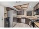 Galley kitchen with stainless steel refrigerator and dishwasher, dark wood cabinets, and a window over sink at 7426 W Cholla St, Peoria, AZ 85345