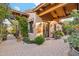 Picturesque covered entrance with decorative tile work, a security gate, desert landscaping, and mature plantings at 7846 E Wilderness Trl, Gold Canyon, AZ 85118