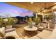 Covered patio boasts comfortable seating and views of the pool at sunset at 7846 E Wilderness Trl, Gold Canyon, AZ 85118
