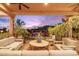 Inviting covered patio featuring comfortable seating, lush plants, and a tranquil view of the pool at sunset at 7846 E Wilderness Trl, Gold Canyon, AZ 85118