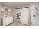 Bright bathroom featuring a vanity, shower with marble accents, and a sliding barn door entrance to the main bedroom at 8030 W Griswold Rd, Peoria, AZ 85345