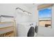 Bright laundry room with modern appliances, storage shelves, and a large window at 8030 W Griswold Rd, Peoria, AZ 85345