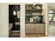 Stylish bar area with custom shelves, tile backsplash, and modern cabinets at 8910 E Topeka Dr, Scottsdale, AZ 85255