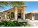 A grand entrance to a desert home with a tile roof, mature landscaping and a three-car garage at 8910 E Topeka Dr, Scottsdale, AZ 85255