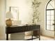 Close-up of home office with black desk, white chair, arched window and decorative plants and accessories at 8910 E Topeka Dr, Scottsdale, AZ 85255