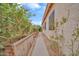 View of the property's side yard featuring a walkway, garden beds, lush foliage, and home exterior at 8968 W Adam Ave, Peoria, AZ 85382