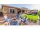 Private backyard features a fire pit with Adirondack chairs, manicured turf, and covered patio at 9764 E Thornbush Ave, Mesa, AZ 85212