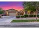 Stunning exterior view of the home showcasing a three-car garage, desert landscaping, and a colorful sunset at 9764 E Thornbush Ave, Mesa, AZ 85212