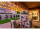 Relaxing covered patio with string lights and outdoor seating, overlooking a well-manicured backyard at 9764 E Thornbush Ave, Mesa, AZ 85212
