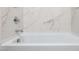 Modern bathtub with elegant marble tile surround and chrome fixtures at 10608 W Sonrisas St, Tolleson, AZ 85353