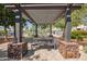Community pergola featuring string lights, picnic tables, and rock-filled planters, with pool in the background at 14180 W Willow Ave, Surprise, AZ 85379