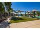 Community pool area featuring lounge chairs, umbrellas, grassy area, and splash pad for a Gathering-friendly recreation space at 14180 W Willow Ave, Surprise, AZ 85379
