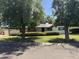 Suburban home with verdant lawn and mature trees casting shadows across the front yard at 1447 E Town And Country Ln, Phoenix, AZ 85014
