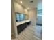 Modern bathroom with a gray vanity, a white countertop, decorative mirrors, and a walk-in shower at 17324 W Royal Palm Rd, Waddell, AZ 85355