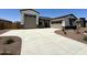 Home featuring a two-car and single-car garage, a concrete driveway, and neutral exterior color schemes with stone accents at 17324 W Royal Palm Rd, Waddell, AZ 85355