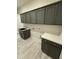 Laundry room featuring gray cabinets, a countertop, a stainless steel farmhouse sink, and white doors at 17324 W Royal Palm Rd, Waddell, AZ 85355