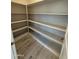 Walk-in pantry with bright white shelving, light-colored wood-look tile flooring, and neutral colored walls at 17324 W Royal Palm Rd, Waddell, AZ 85355