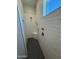Modern shower stall with gray tile floor, subway tile surround, bench, and vertical window allowing natural light at 17324 W Royal Palm Rd, Waddell, AZ 85355