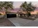 Charming single-story home boasts a dark-toned garage door, desert landscaping, and a warm, inviting entrance at dusk at 1736 N Ashbrook Cir, Mesa, AZ 85213
