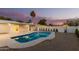 The backyard oasis features a sparkling pool, privacy fence, desert landscape, and palm trees at sunset at 1736 N Ashbrook Cir, Mesa, AZ 85213