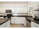 Bright kitchen features white cabinets, black appliances, and dark countertops at 17613 N 114Th Ln, Surprise, AZ 85378
