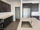 Modern kitchen with dark cabinets, white countertops, stainless steel appliances, and pantry at 17989 W Lupine Ave, Goodyear, AZ 85338