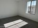 A bright bedroom with gray carpeting and one window with a shadow at 18061 W Lupine Ave, Goodyear, AZ 85338