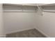 An empty, walk-in closet with neutral carpet and a wood closet rod at 18061 W Lupine Ave, Goodyear, AZ 85338